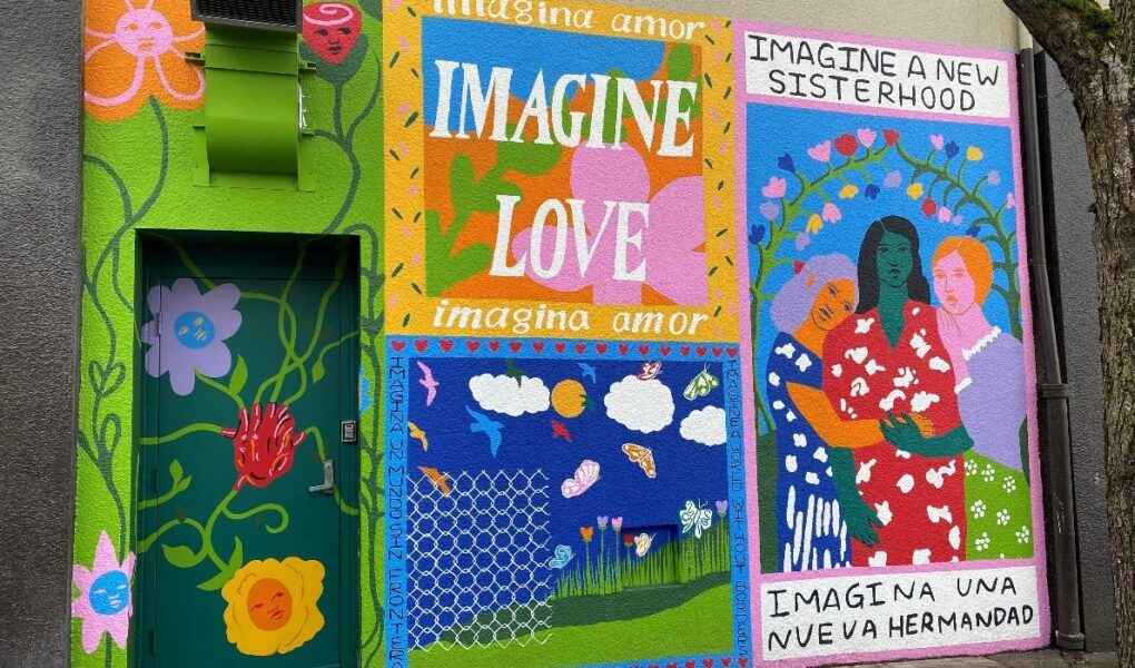 Photo of colorful mural on a building. Includes vines, human figures and the words "Imagine Love"